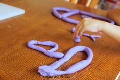 a young child is making letters out of pipe cleaner