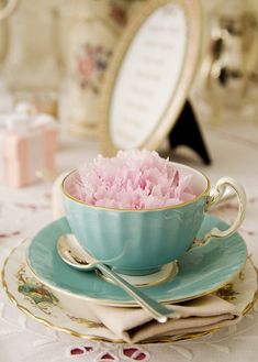 a teacup with pink carnations sits on a table