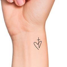 a woman's arm with a cross and heart tattoo on the left side of her wrist