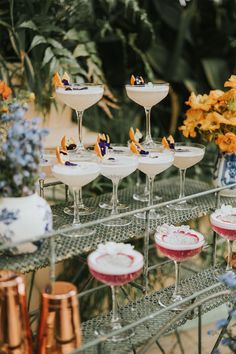 there are many desserts on the table with flowers in vases and glasses filled with them