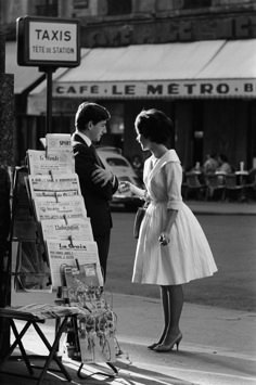 a man and woman standing next to each other in front of a sign