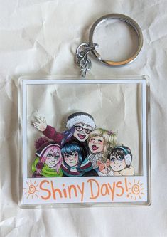 a keychain with the words shiny days on it and an image of cartoon characters