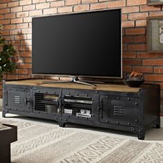 a flat screen tv sitting on top of a wooden stand in front of a brick wall