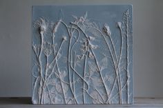 a ceramic tile with flowers on it sitting on top of a wooden table next to a wall