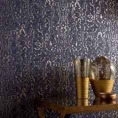 two vases are sitting on a table in front of a wallpapered background