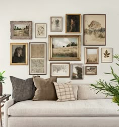 a living room filled with lots of framed pictures on the wall next to a couch