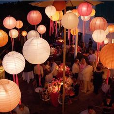 a group of people sitting around tables under paper lanterns