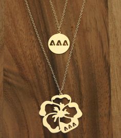 two necklaces with the letters aa, aa and aa on them hanging from a wooden surface