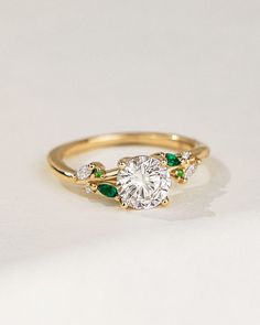 a diamond and emerald ring on a white surface