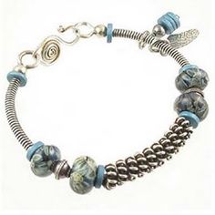 a bracelet with blue beads and silver accents on the clasp is shown in front of a white background