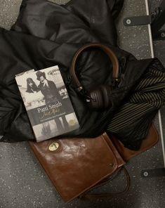 a book, headphones and purse sitting on the ground