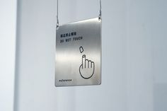 a metal sign hanging from the side of a white wall that says do not touch