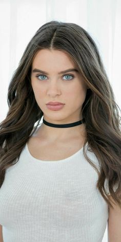 a woman with long brown hair wearing a choker and white shirt is looking at the camera