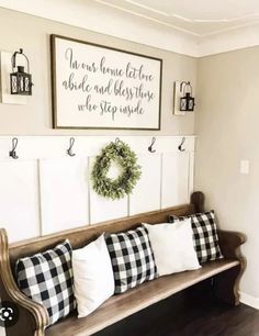 a wooden bench with pillows on it in front of two framed pictures and a wreath