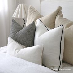 pillows and lamps on a bed with white linens