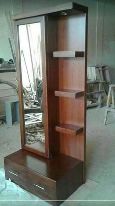 a tall wooden cabinet sitting inside of a room next to a mirror on the floor