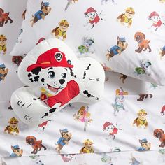 a stuffed animal laying on top of a bed covered in cartoon character sheets and pillows