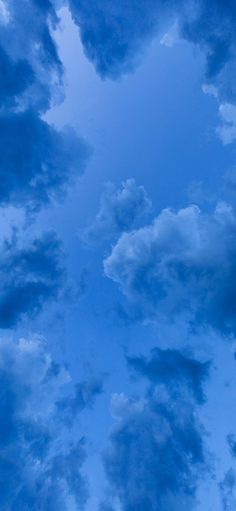 an airplane is flying through the blue sky with clouds in the background