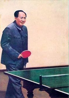 a man standing next to a ping pong table