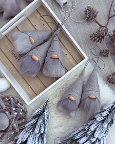 three gray cones are sitting in a box next to some pine cones and other decorations