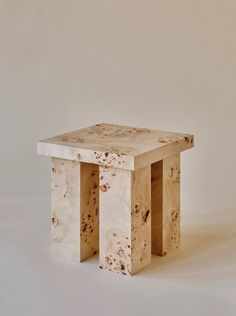 a small wooden table sitting on top of a white floor next to a brown wall