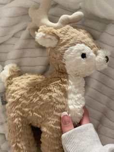 a person holding a stuffed animal that looks like a fawnish deer with antlers on it's head