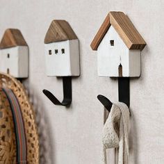 three wooden birdhouses mounted to the side of a wall next to a hat rack