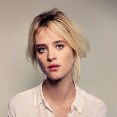 a woman with blonde hair and blue eyes wearing a white shirt looking at the camera