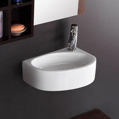 a white bathroom sink sitting next to a wall mounted faucet and soap dispenser