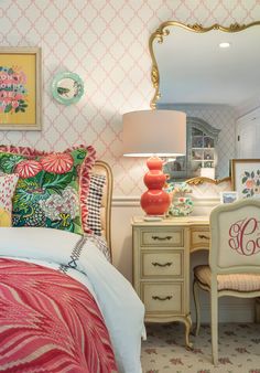 a bedroom decorated in pink, green and white with an ornate gold framed mirror on the wall