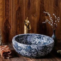 a bowl shaped sink sitting on top of a wooden table next to a vase with flowers