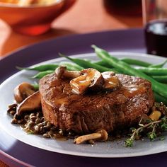 a steak with mushrooms and green beans on a plate