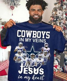 a man holding up a cowboys t - shirt in front of a christmas tree with his name