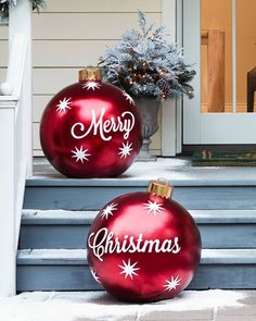 two red christmas ornaments sitting on the steps next to each other in front of a house