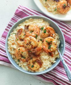 shrimp and grits in a bowl with a fork next to it on a striped dish towel