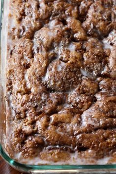 a close up of a casserole dish with cinnamon rolls in the center and icing on top