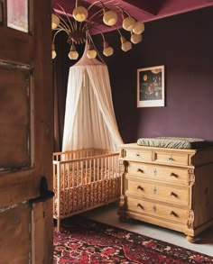 a crib and dresser in a room with purple walls