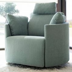 a blue recliner chair sitting on top of a white rug in front of a window