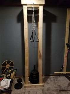 a wooden clock tower with two bells hanging from it's sides in a room