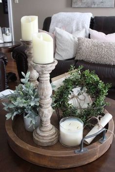 a tray with candles, greenery and other items on it in a living room