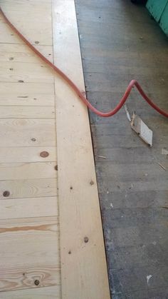 a red hose is connected to the side of a wooden floor with wood planks