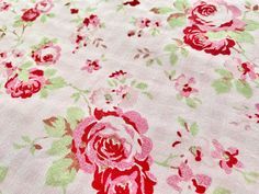 a pink and green flowered fabric with red flowers on it