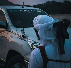 a person wearing a white outfit standing in front of a car with writing on it