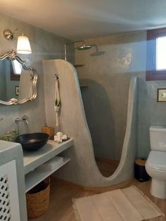 a bathroom with a toilet, sink and shower in it's corner area next to a window