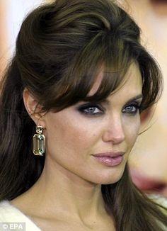 a close up of a person with long hair and blue eyes wearing earrings on her head