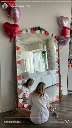 a woman sitting on the floor in front of a mirror with balloons attached to it