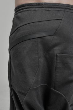 "DISTORTED ANTHRACITE DROPPED CROTCH TRACK PANTS WITH ELASTIC WAISTBAND __ELASTIC WAISTBAND WITH DRAWSTRING __J SHAPED LEGS __2 FRONT POCKETS __2 REAR BONDED POCKETS __ASYMMETRICAL HIDDEN FRONT CLOSURE model__ chest 103 (40.5\"), waist 77 (30.3\"), hips 96 (37.8\"), biceps 35 (13.8''), height 180 (5'11\"), kg 74 (163 lbs) model wears size S | color: anthracite with black matte tape fabric__ 100 cotton care__ delicate machine wash at 30 c wash inside out use cool iron do not tumble dry sizing__ s Futuristic Pants, Urban Clothing Men, Low Crotch Pants, Sporty Leggings, Winter Tights, Track Pants Mens, Mens Tights, Track Pant, Wool Pants