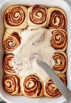 a pan filled with cinnamon rolls covered in icing