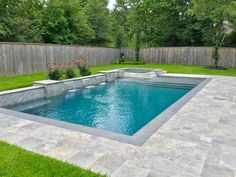 a pool in the middle of a yard with grass around it and flowers on either side