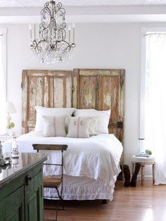 a bedroom with a bed, chandelier and wooden headboard in the corner